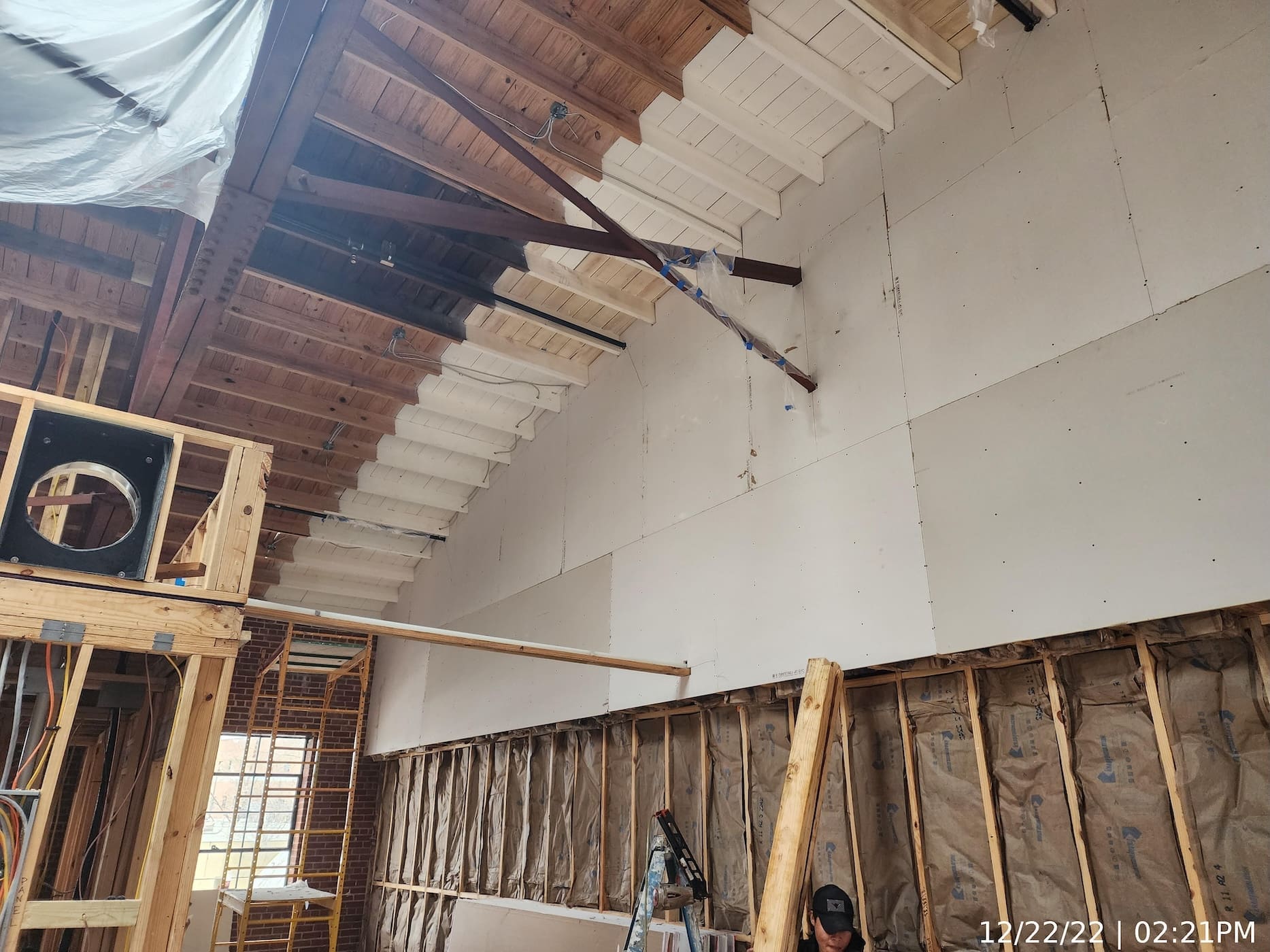 Drywall continues at fire-rated demising wall. Intumescent paint applied at areas where wood-framed roof abuts fire wall.